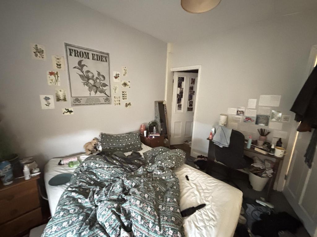 A cozy bedroom with a slightly cluttered bed ar...