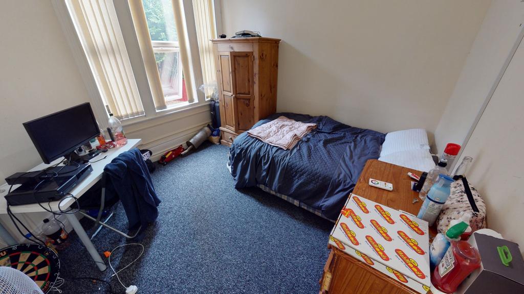 A cozy single bedroom featuring a bed, a desk, ...