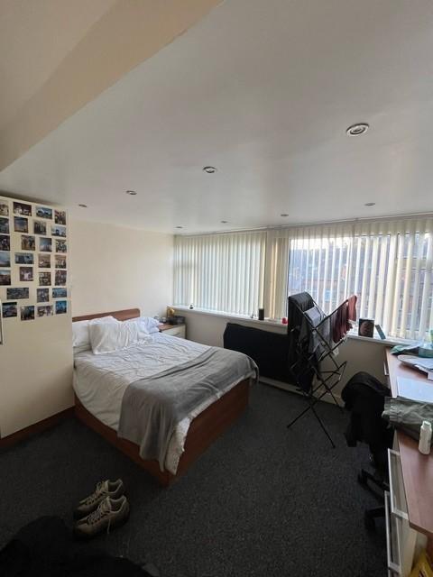 A well-lit master bedroom featuring a comfortab...