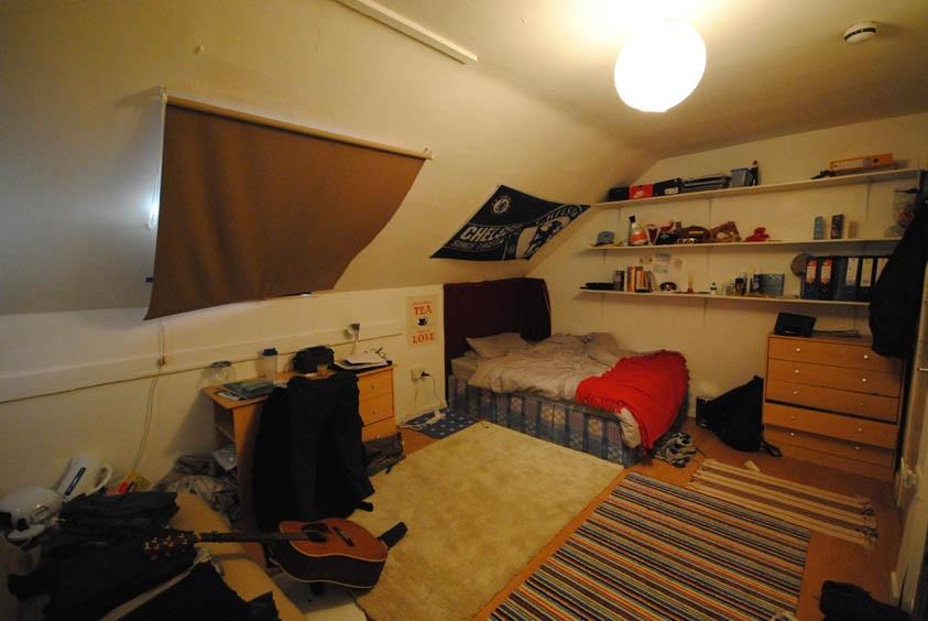 A cozy student bedroom featuring a single bed w...