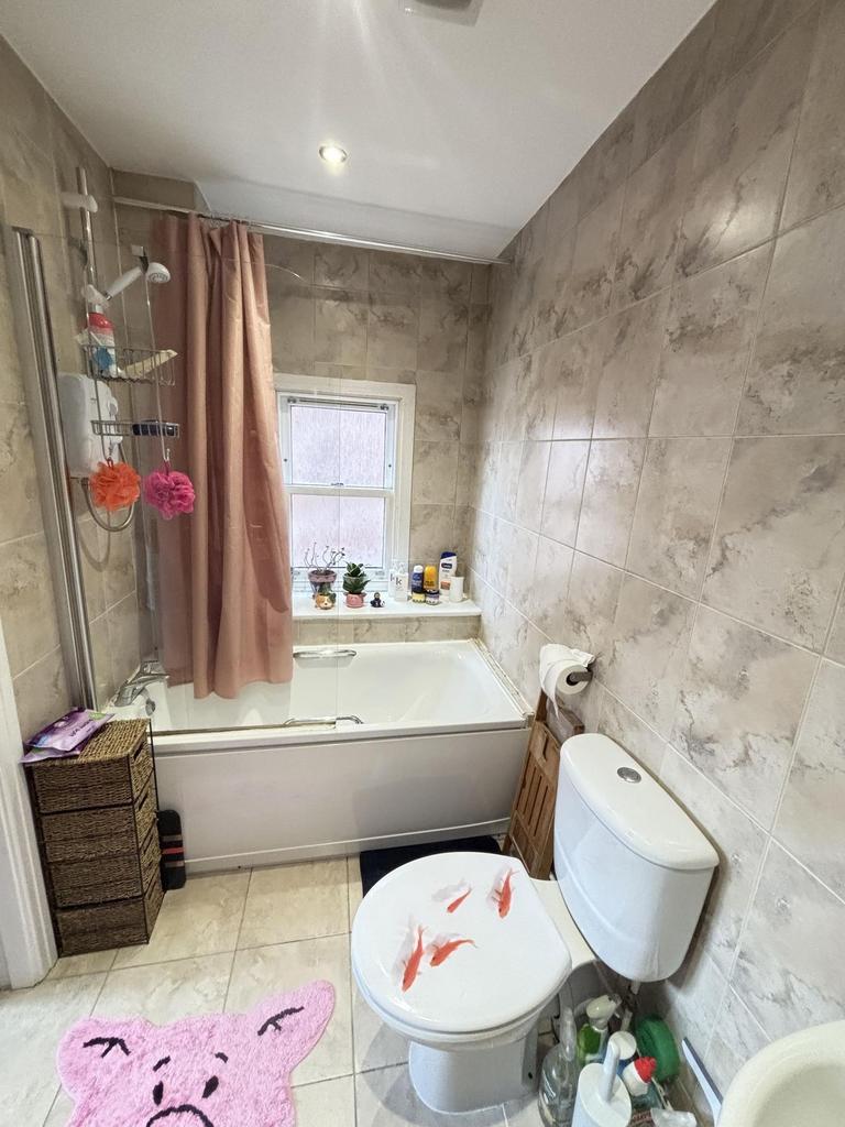 A bright and tidy bathroom featuring a bathtub,...