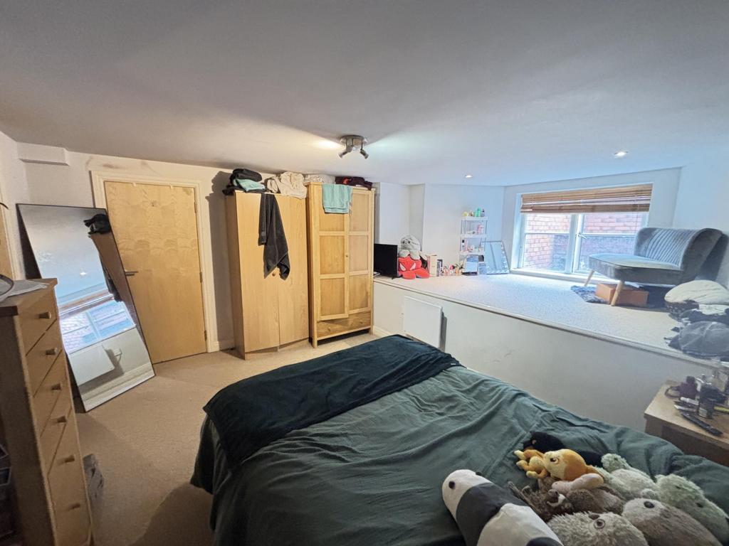 A well-lit bedroom featuring a comfortable doub...