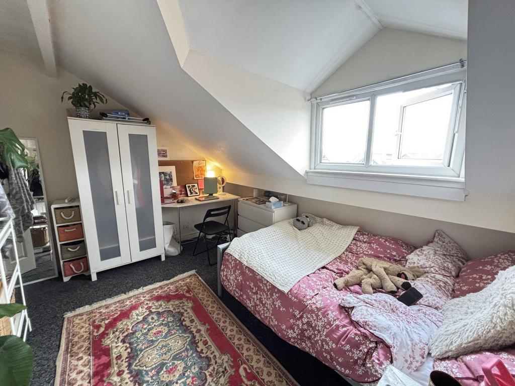 A cozy single bedroom featuring a plush pink be...
