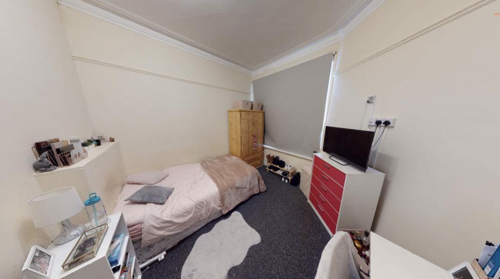 A cozy student bedroom featuring a bed, small w...