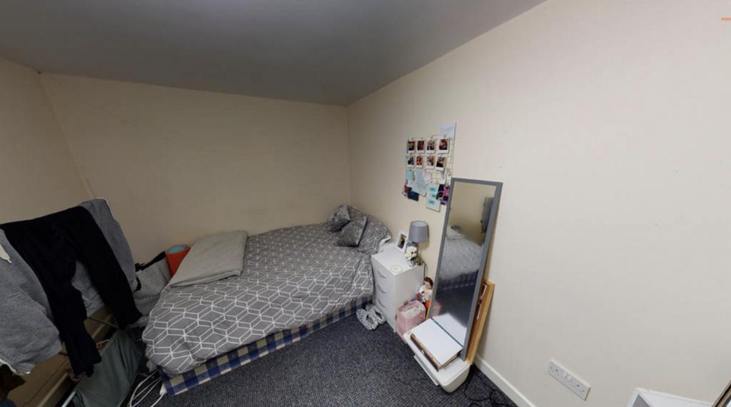 A compact bedroom featuring a bed with patterne...
