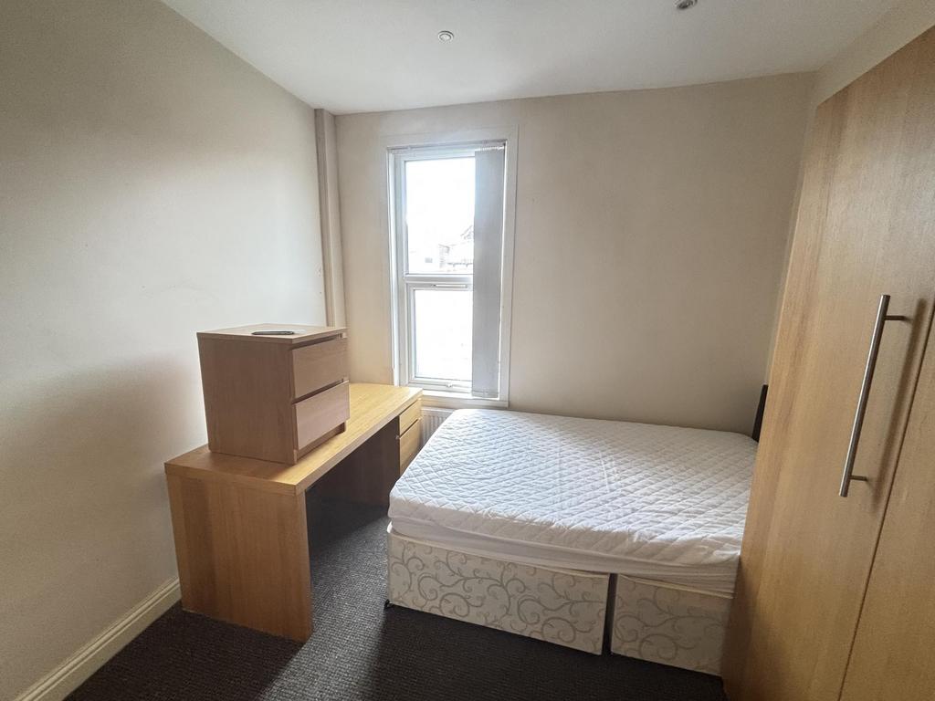 A bright, tidy bedroom featuring a comfortable ...