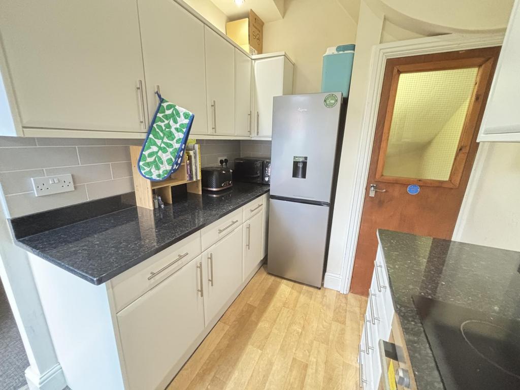 A bright and clean kitchen area with modern cab...