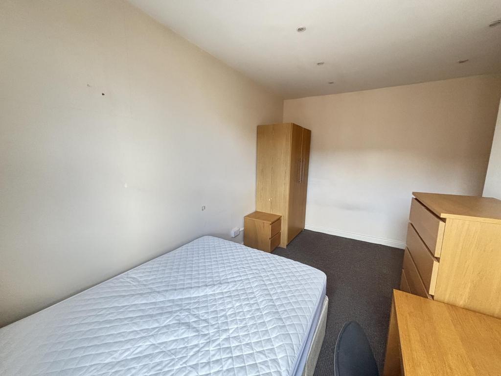 A simple bedroom featuring a double bed, wooden...