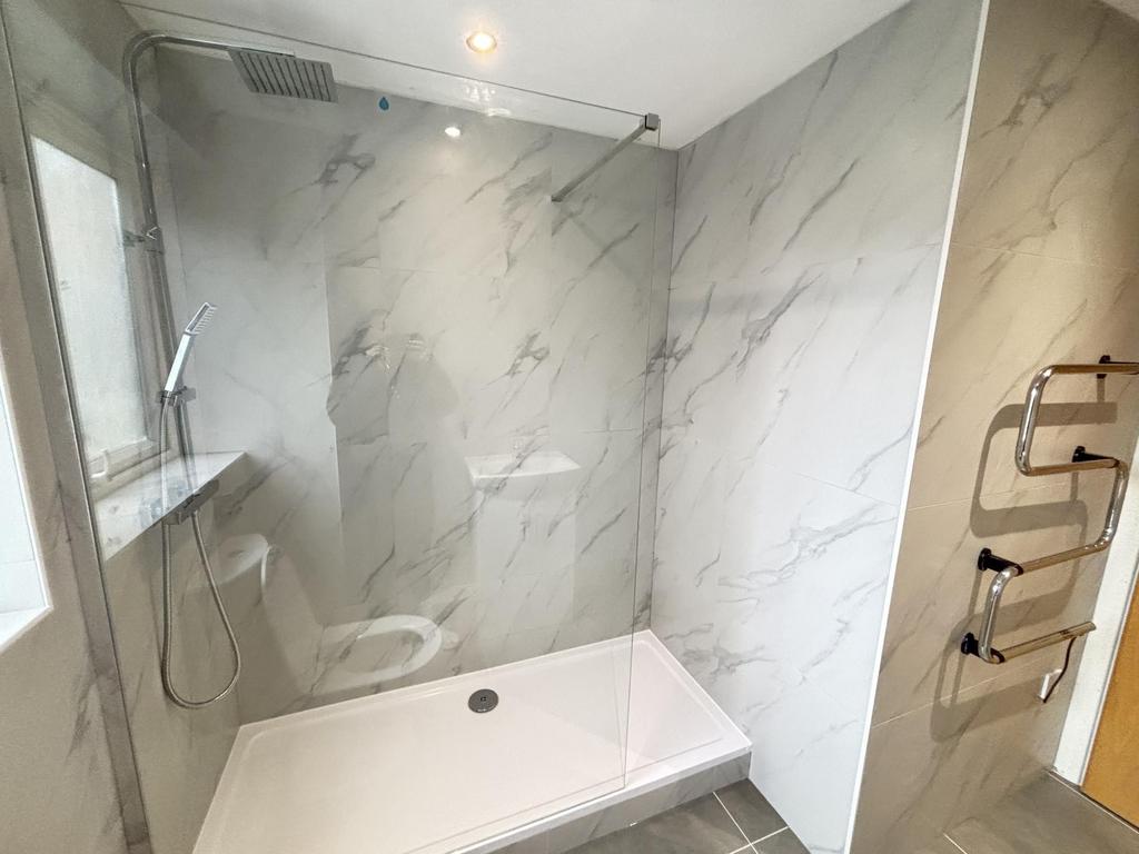 A modern bathroom featuring a spacious shower a...