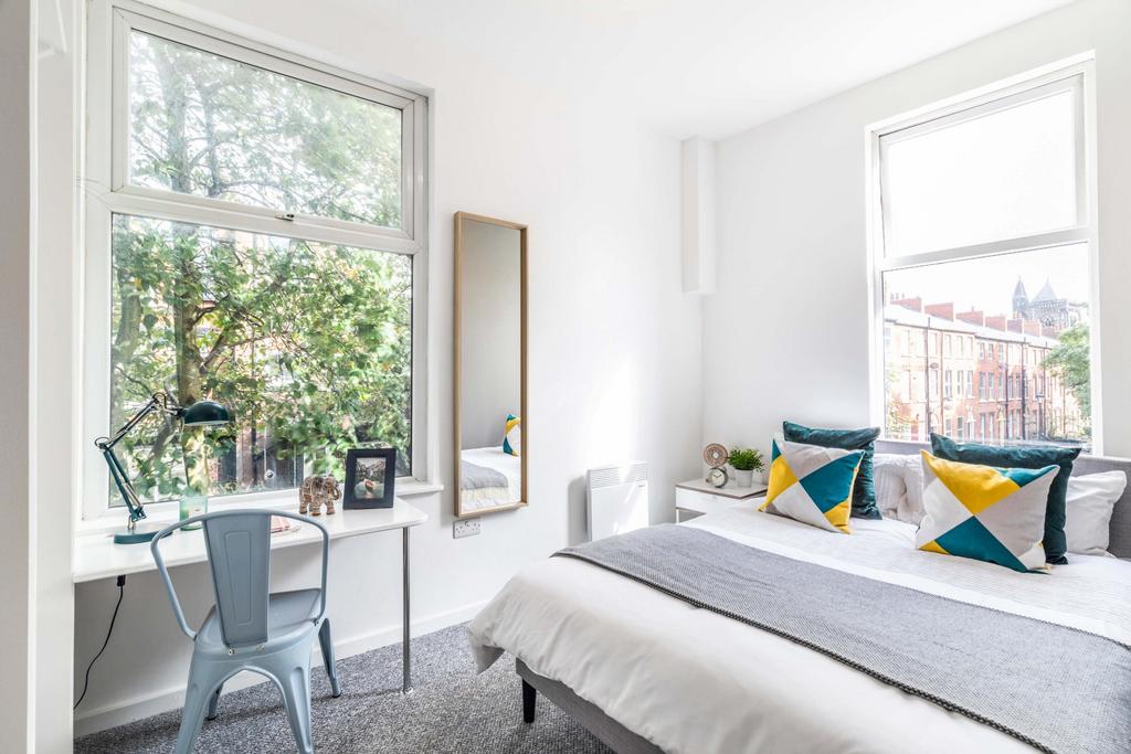A bright, well-lit bedroom featuring a comforta...