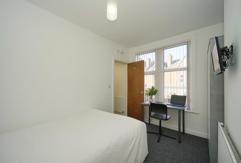 A clean and well-lit bedroom featuring a comfor...