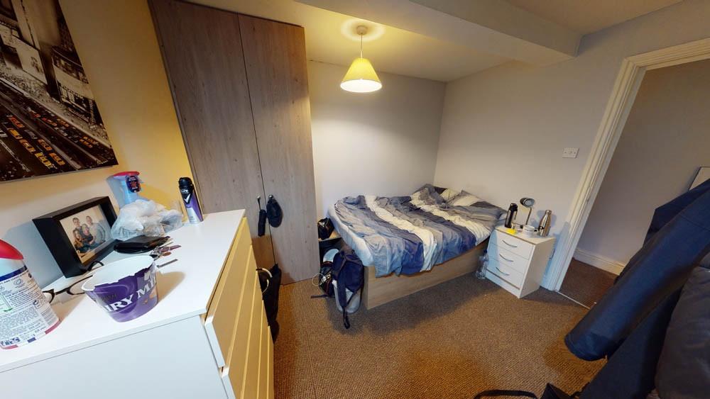 A cozy bedroom featuring a single bed with bedd...