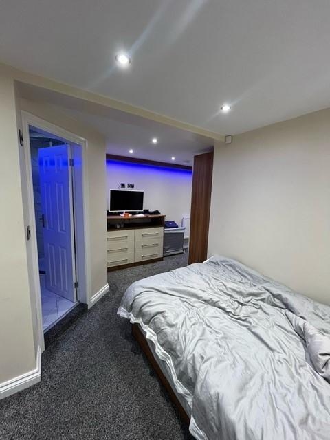 A well-lit bedroom featuring a neatly made bed,...