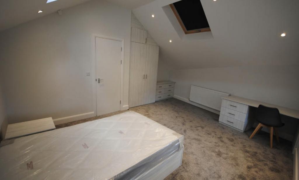 A cozy single bedroom with a neatly made bed, b...