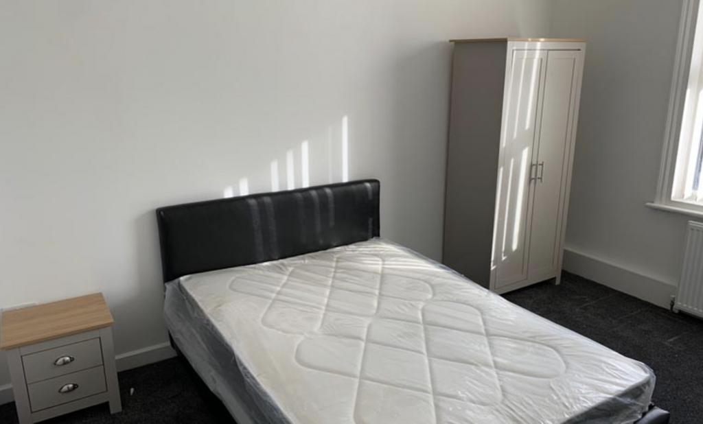 A tidy bedroom with a double bed, black headboa...