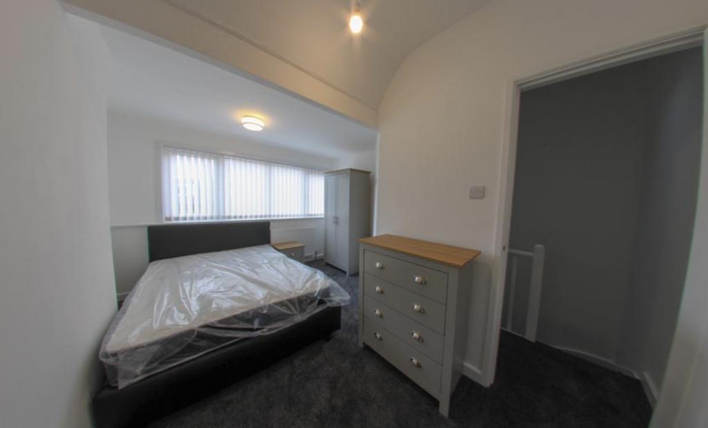 A bright, tidy bedroom featuring a comfortable ...