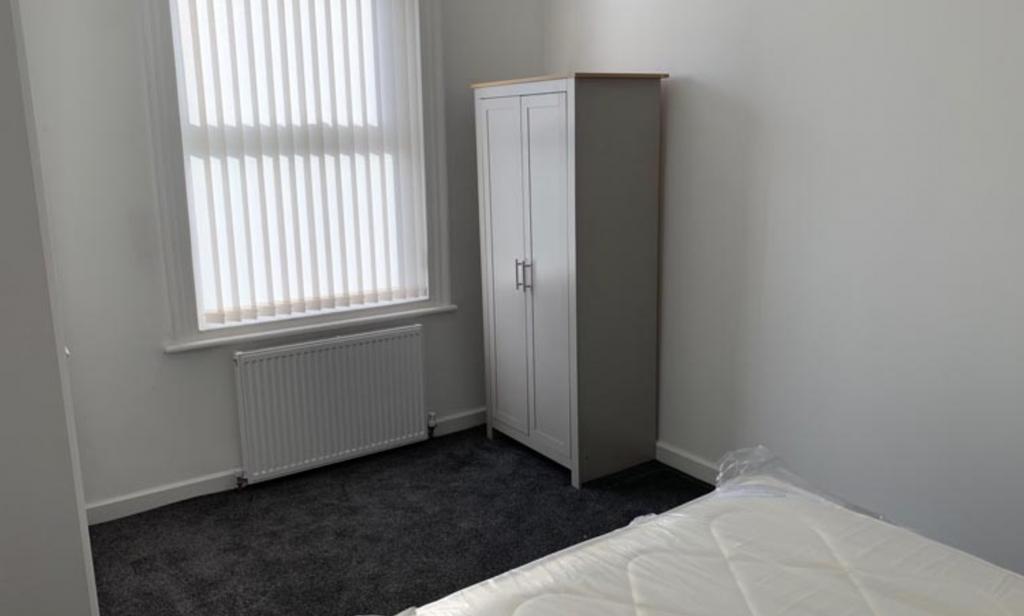 A clean and simple room with a white door and a...