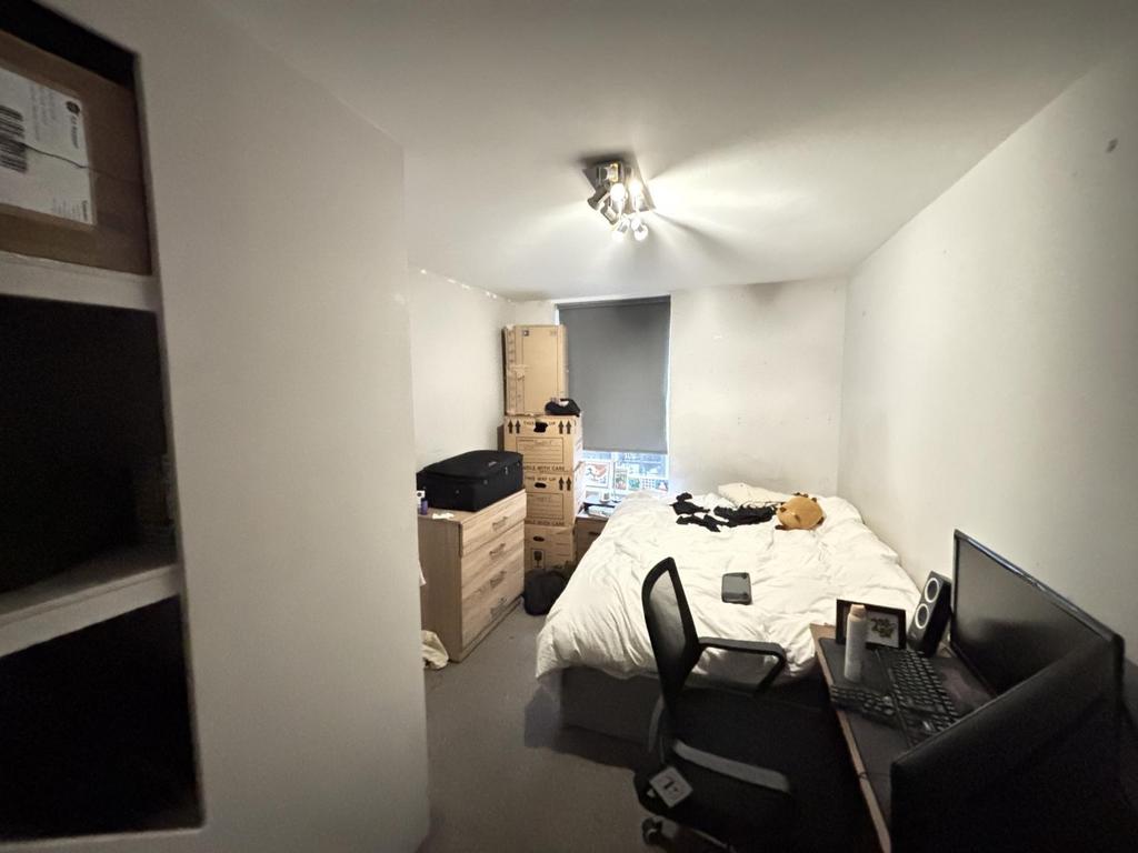 A cozy bedroom featuring a bed, a desk, and som...