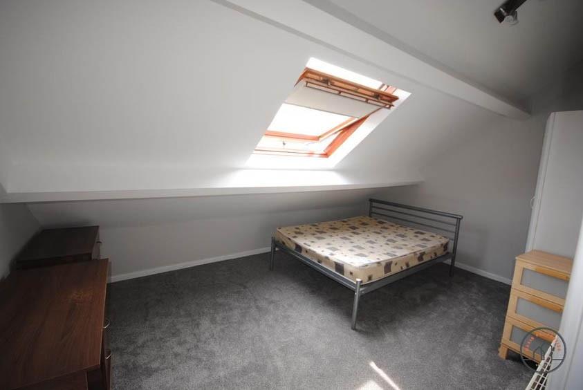 A neatly maintained bedroom with a large skylig...