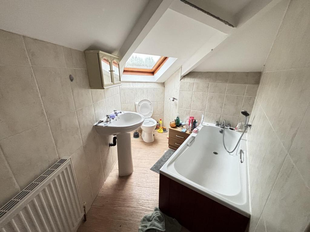 A bright and tidy bathroom with a bathtub and a...