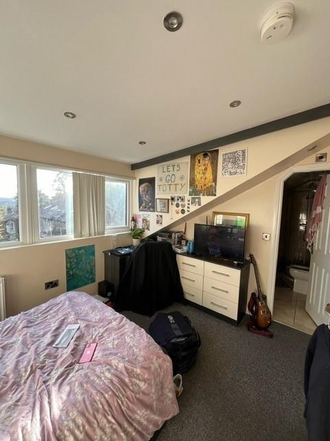 A cozy bedroom featuring a bed with a duvet and...