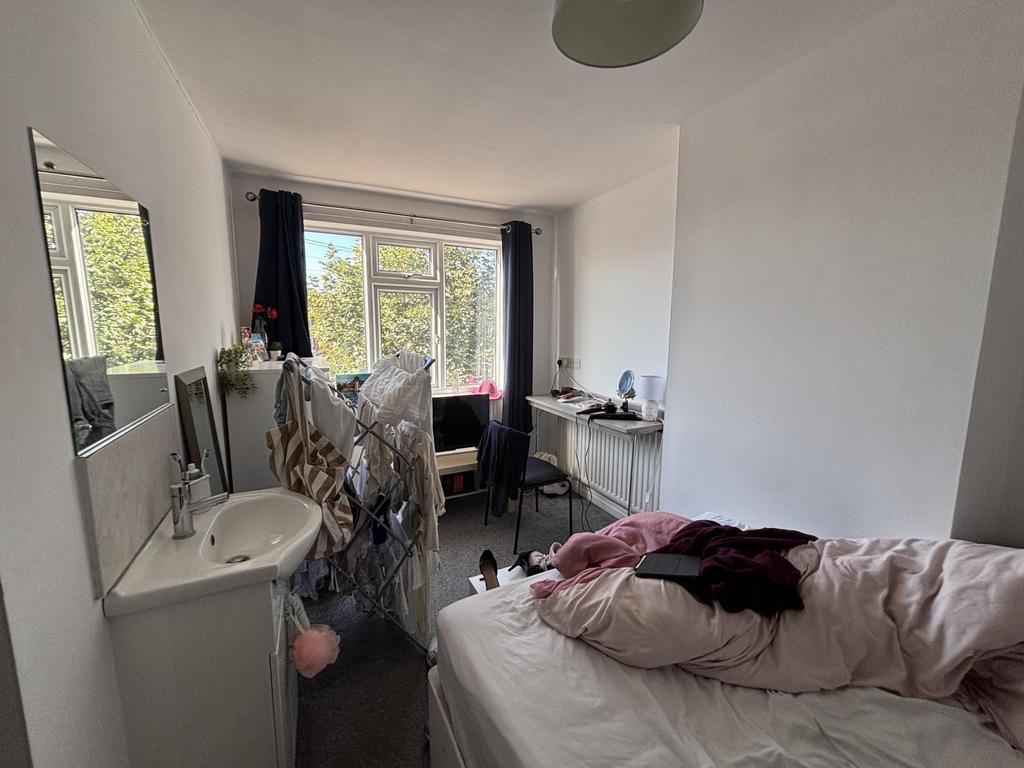 A cozy bedroom featuring a single bed, a small ...
