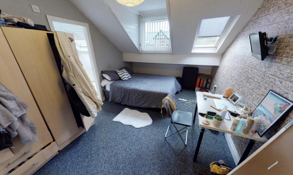 A cozy single bedroom with a neatly made bed, a...