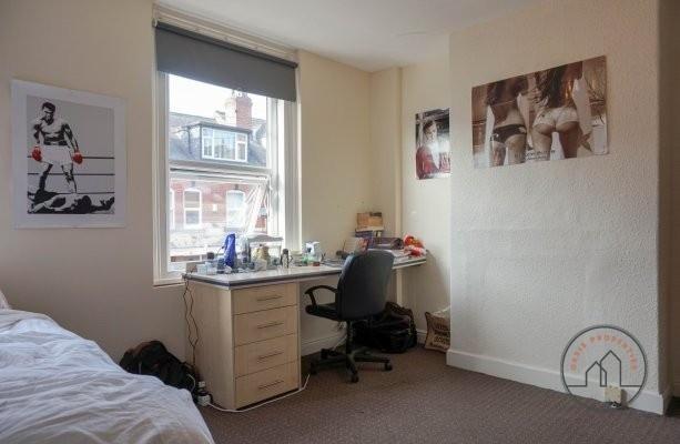 A cozy bedroom featuring a neatly made bed, a d...