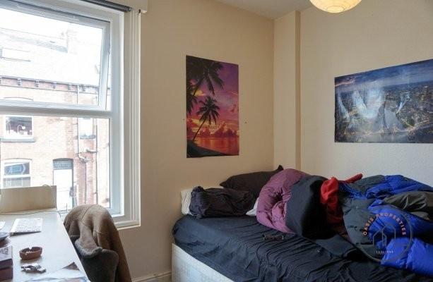 A cozy single bedroom featuring a bed with vari...