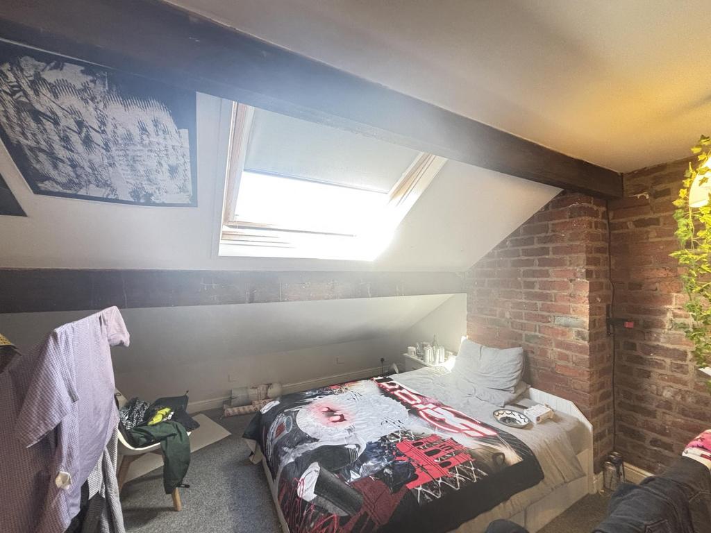 A cozy bedroom with a skylight window allowing ...