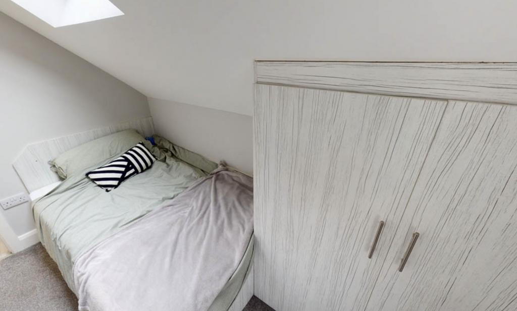 A cozy bedroom featuring a neatly made bed with...