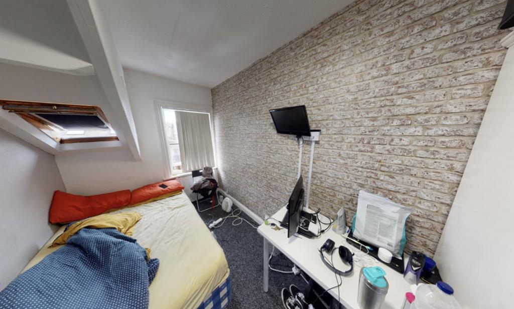 A compact bedroom featuring a bed with bedding,...