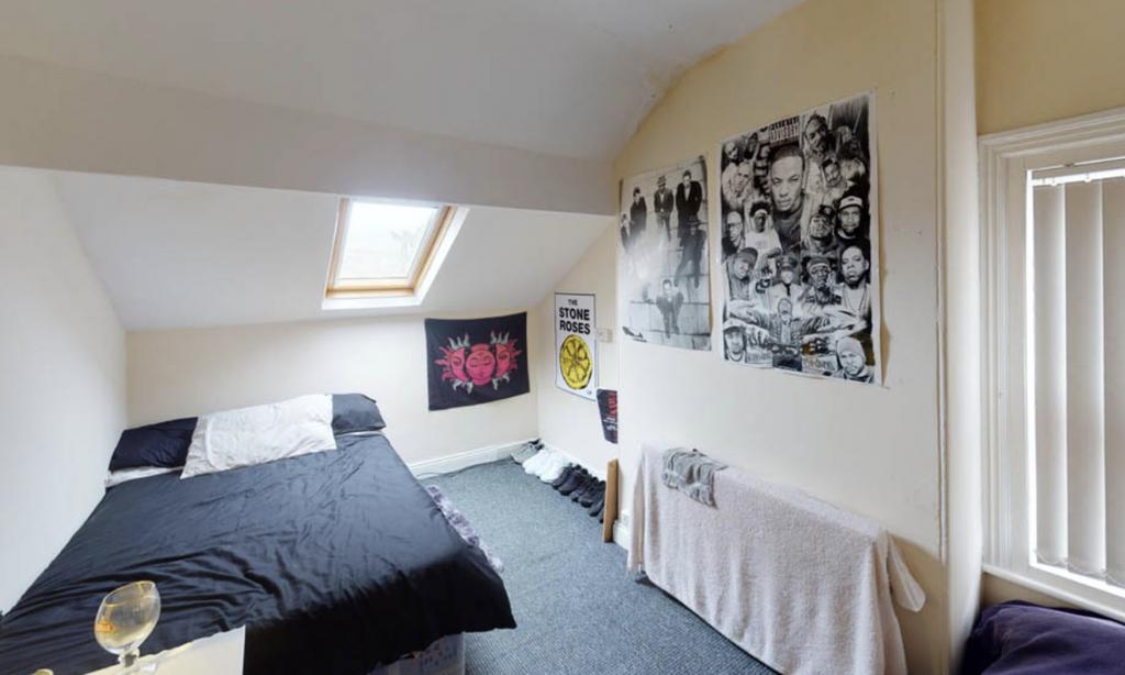 A well-lit, tidy bedroom with a comfortable dou...