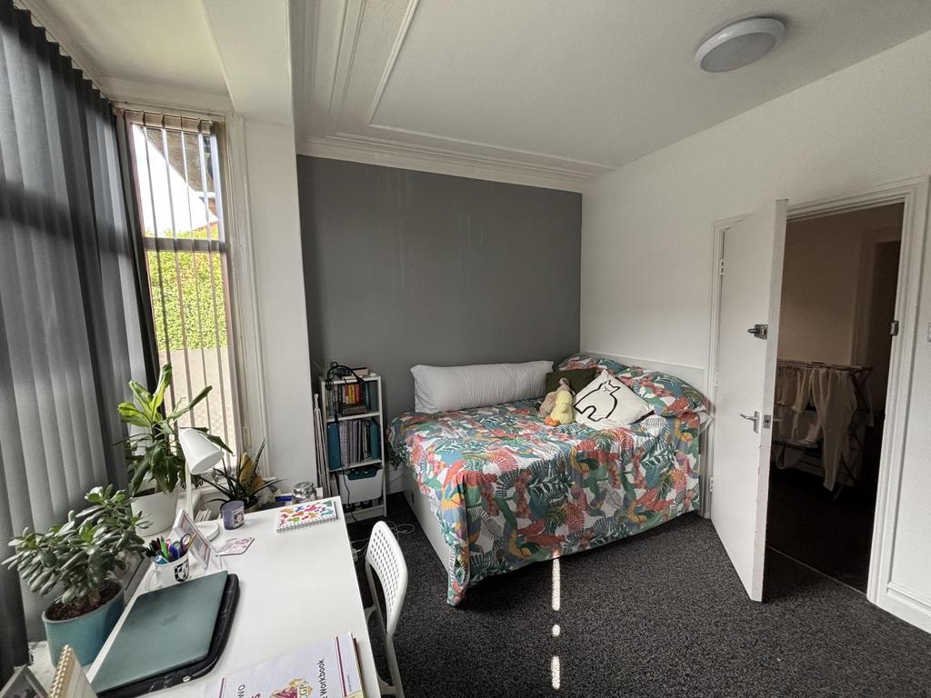 A cozy bedroom featuring a bed with colorful be...
