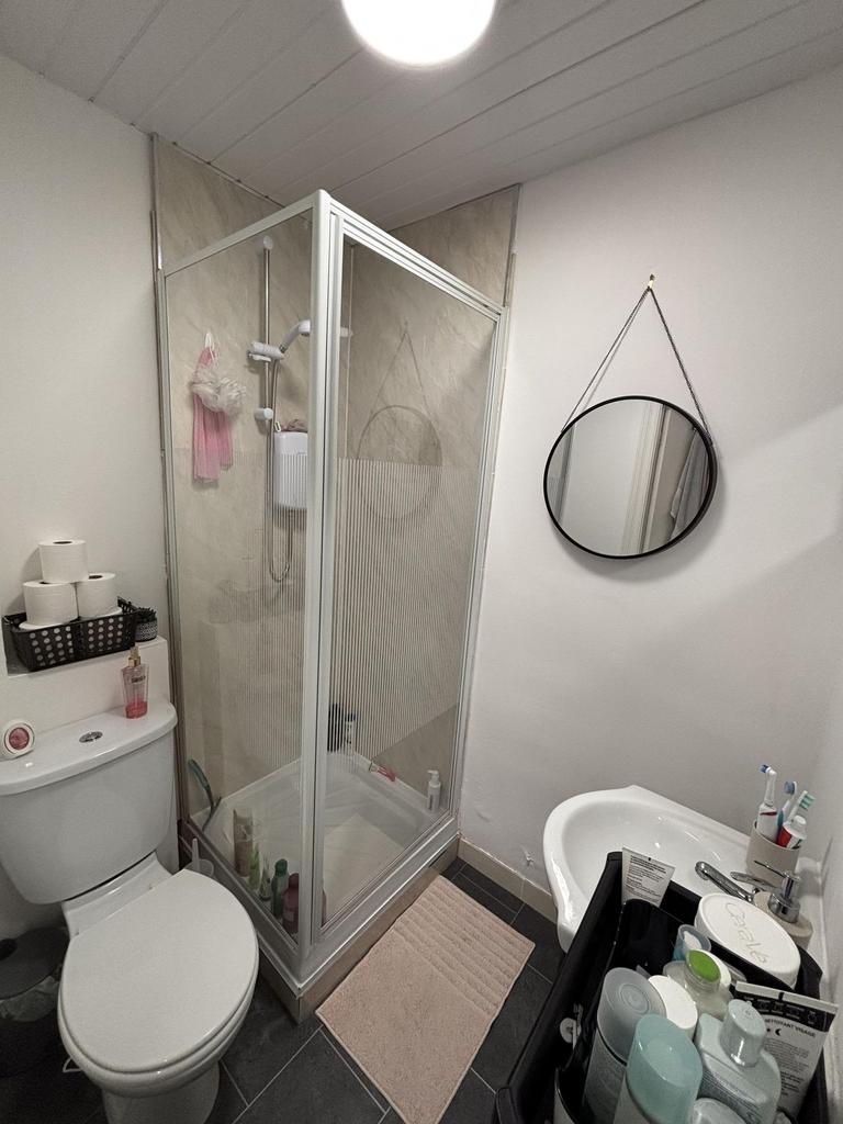 A compact bathroom featuring a shower enclosure...