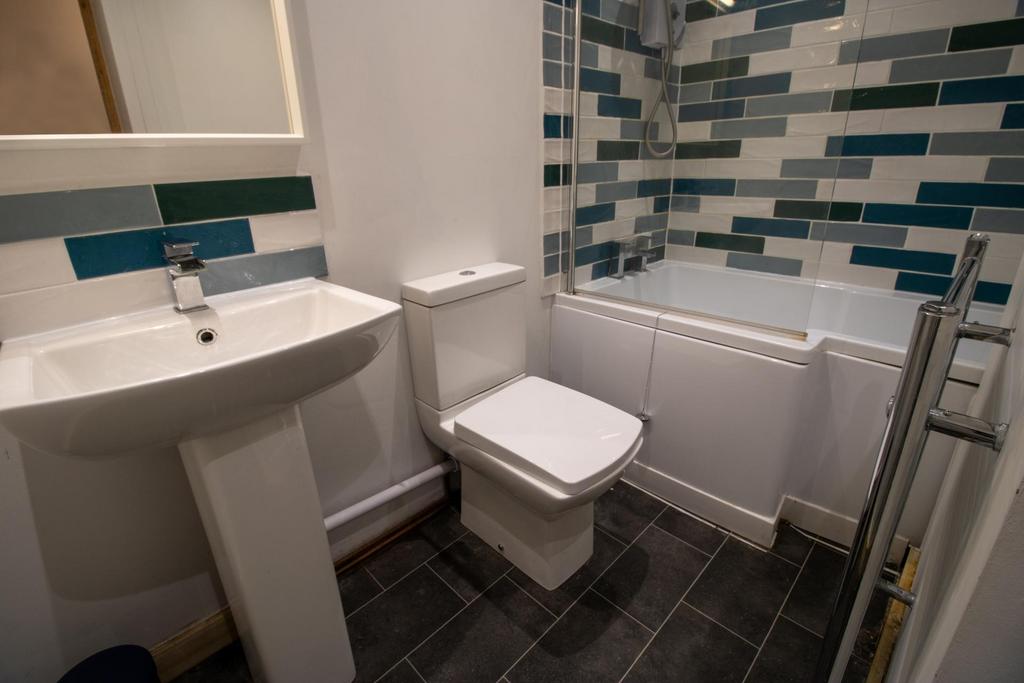 Modern bathroom with patterned tiled bath surro...
