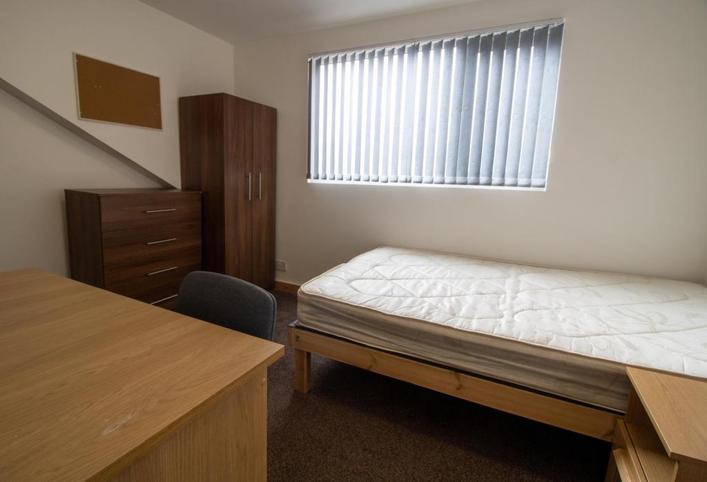 Neat furnished bedroom with a single bed, desk ...