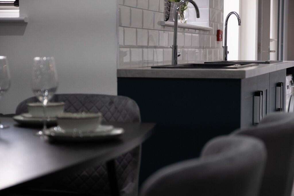 A modern kitchen featuring sleek dark cabinetry...