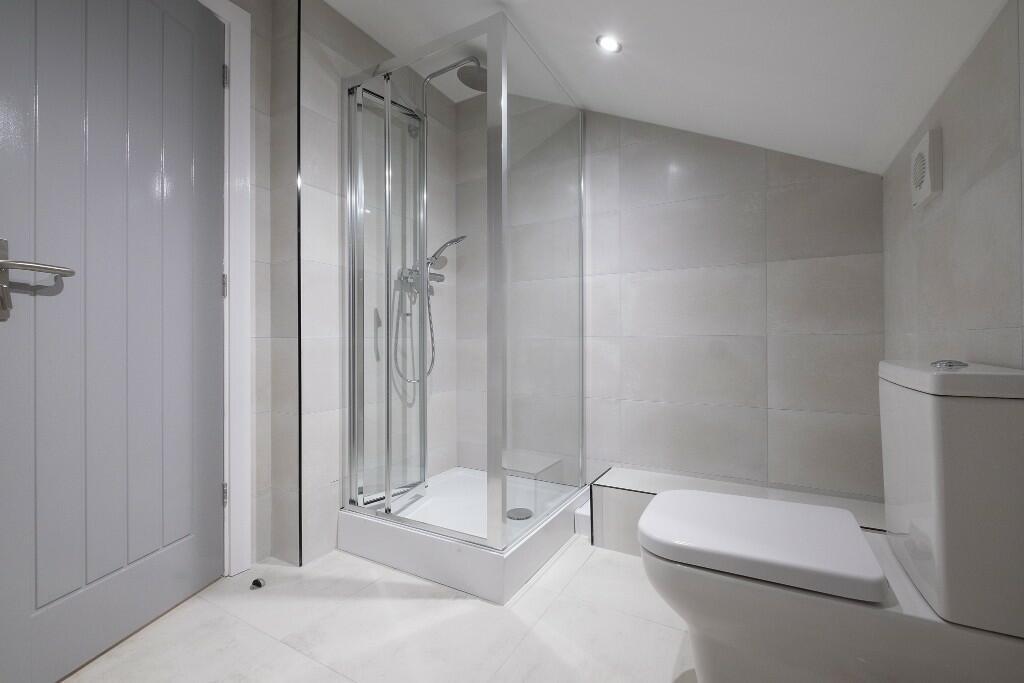 Modern tiled bathroom with a clear glass corner...