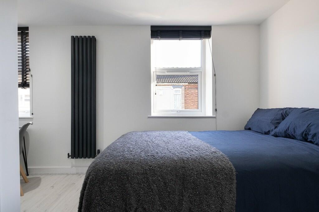 Bright, modern double bedroom with deep blue be...