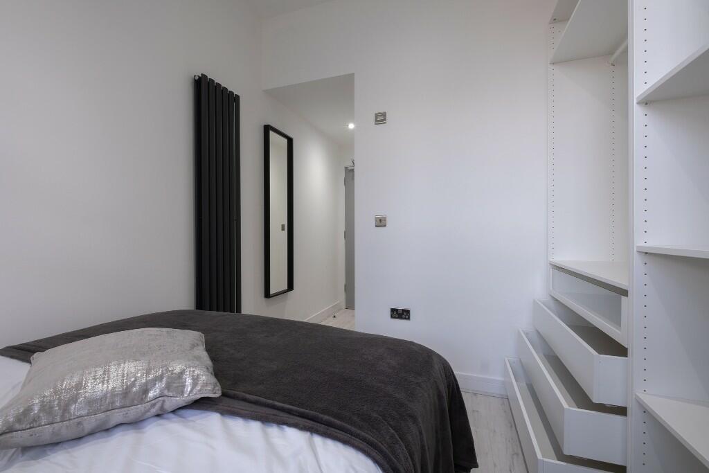 Neat single bedroom with a made bed, built-in s...