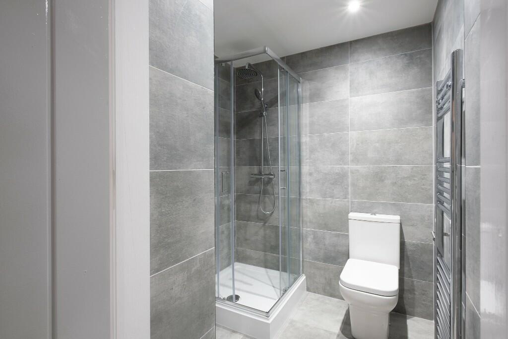 Modern tiled bathroom with a walk-in shower enc...