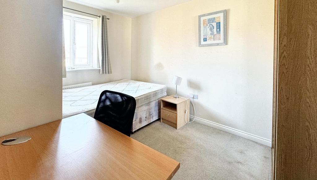 A bright and tidy bedroom featuring a bed, desk...