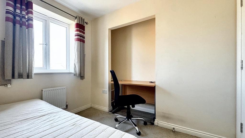 A well-lit bedroom featuring a large window pro...