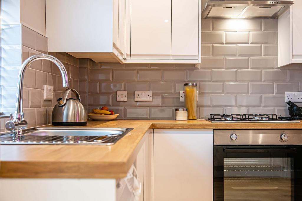 Modern kitchen with white cabinetry, a wooden c...