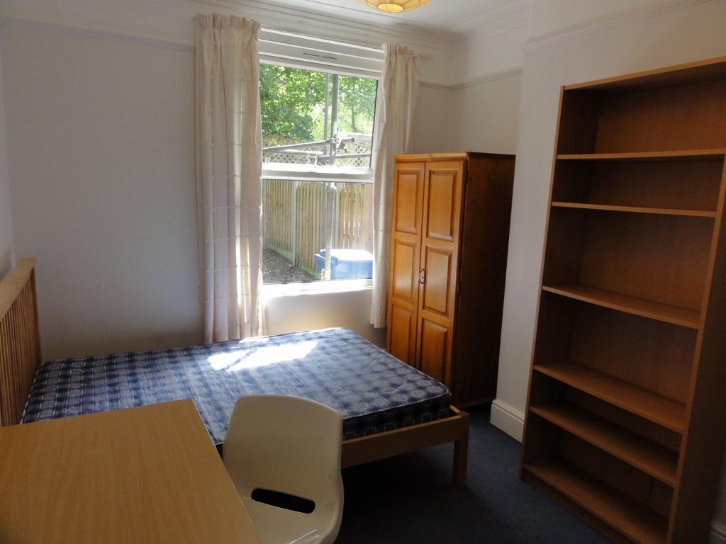 A cozy single bedroom featuring a wooden wardro...