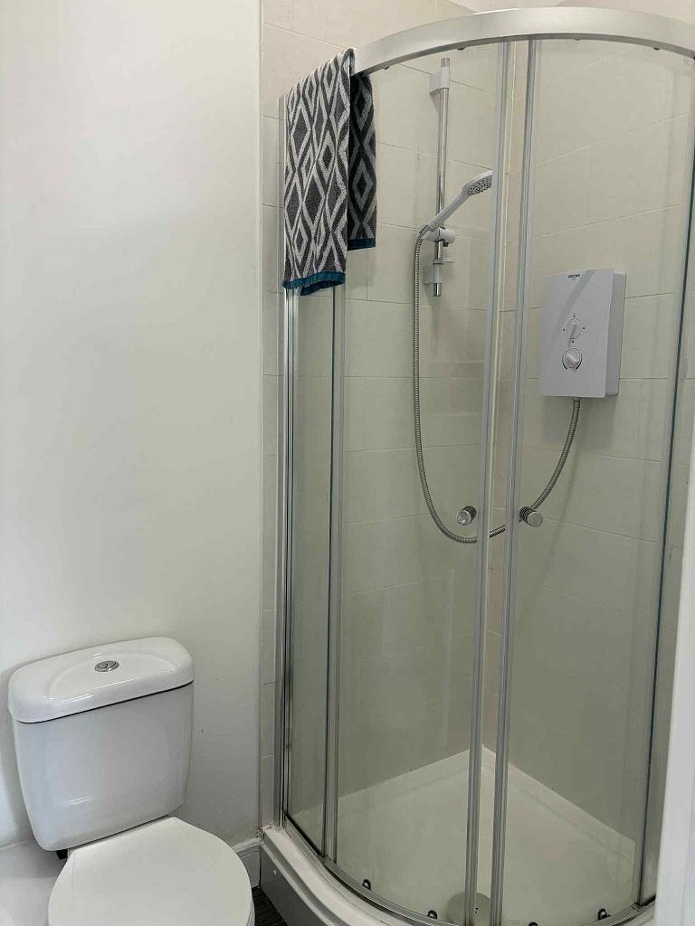 Bright, modern bathroom with a curved glass sho...