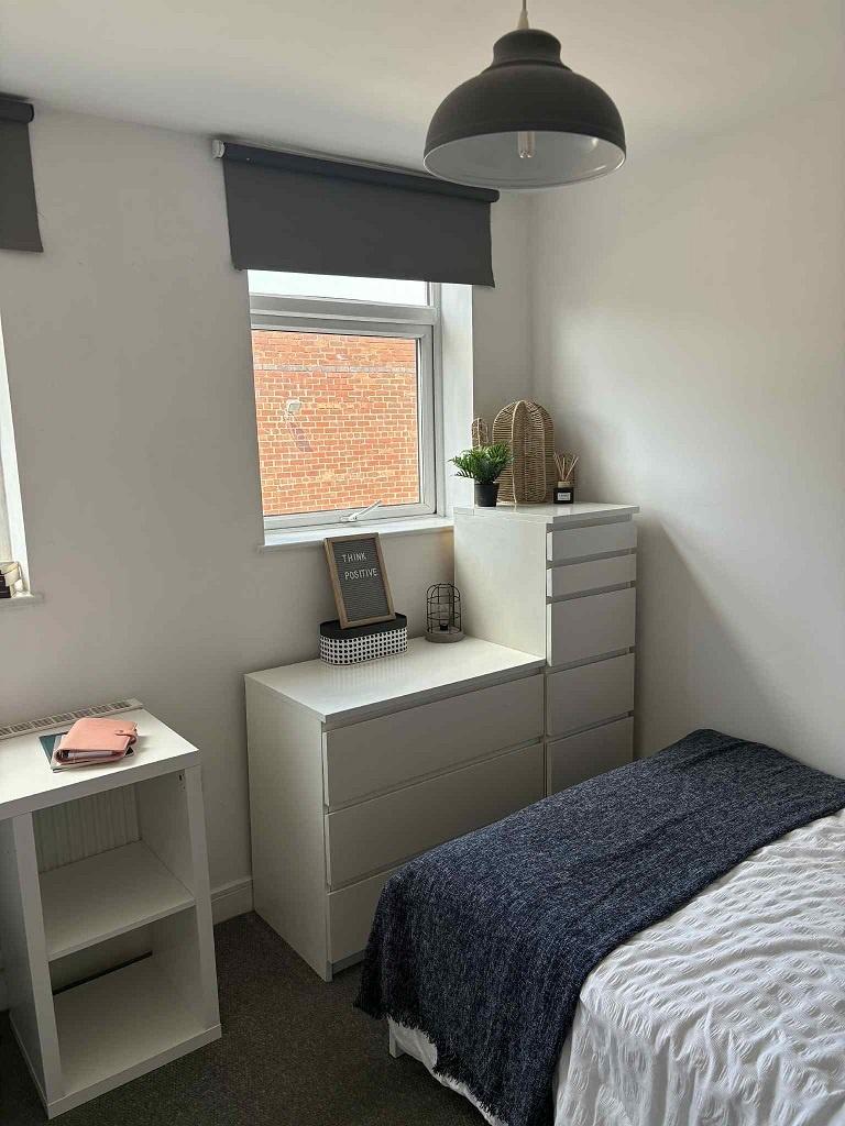 Bright, neatly styled bedroom with a comfortabl...