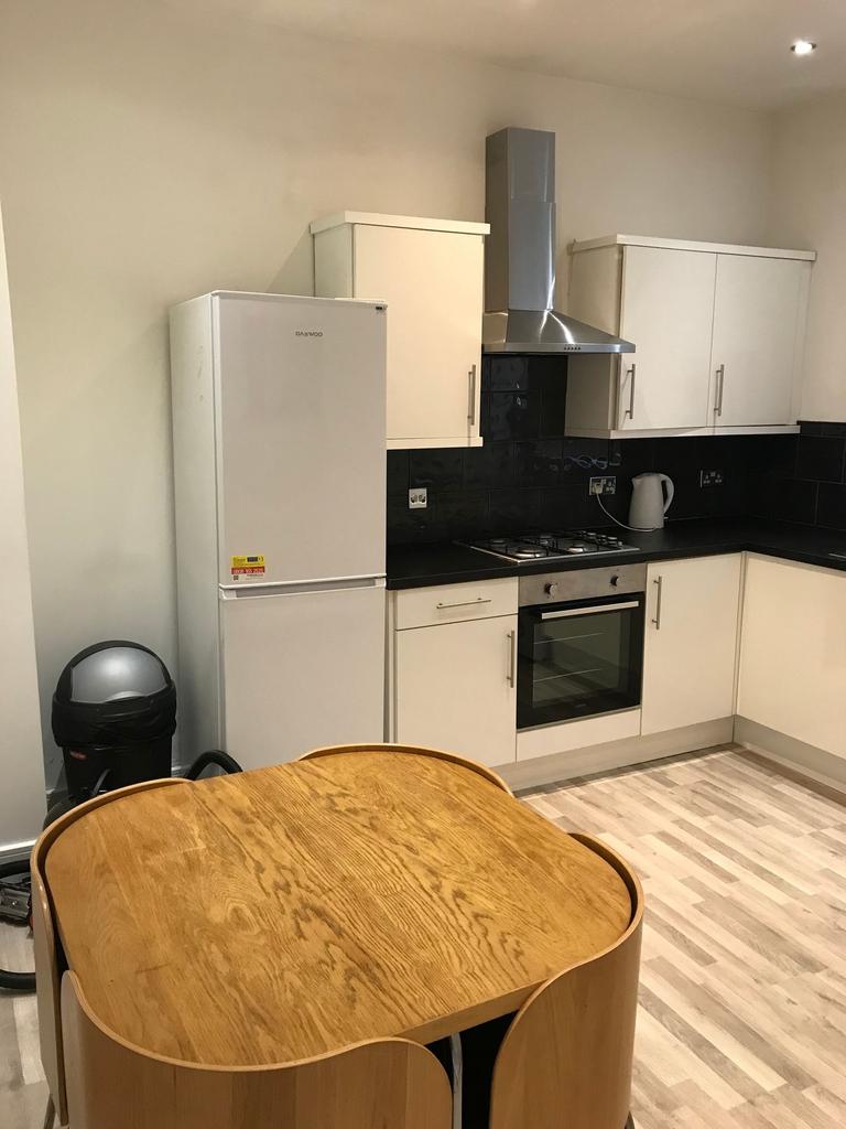 Modern fitted kitchen with white cabinets, blac...