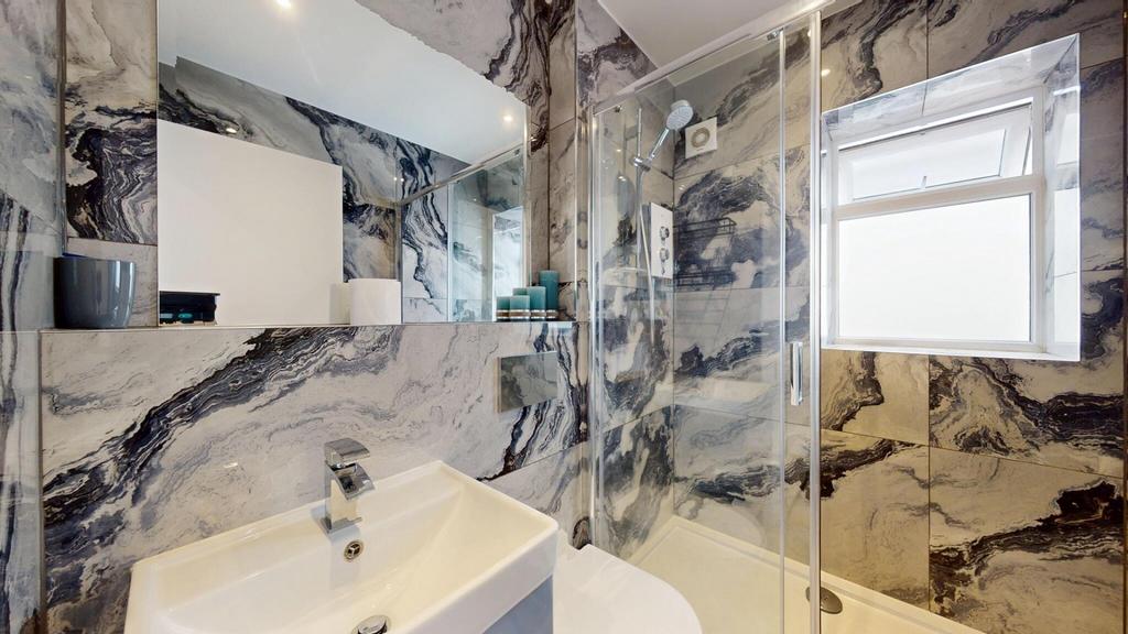 Stylish fully tiled bathroom with striking marb...